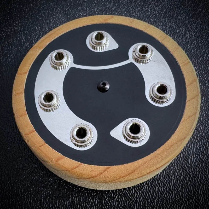 Circular wooden device with 1/8" connectors on top.